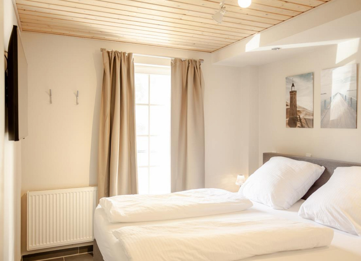 Schlafzimmer im Ferienhaus Seestern in Greetsiel mit Boxspringbett und TV